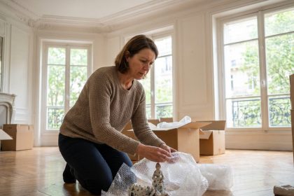 Femme emballant des figurines en porcelaine dans un intérieur parisien