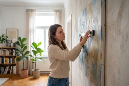Femme accrochant une toile abstraite dans un salon lumineux