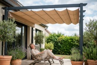 Femme se relaxant sous une pergola aluminium avec store banne beige sur une terrasse moderne