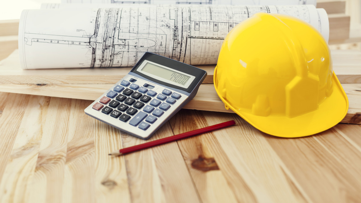 plan de maison accompagné d'une calculatrice et d'un casque de chantier