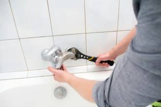 Plombier démontant un robinet dans une salle de bain
