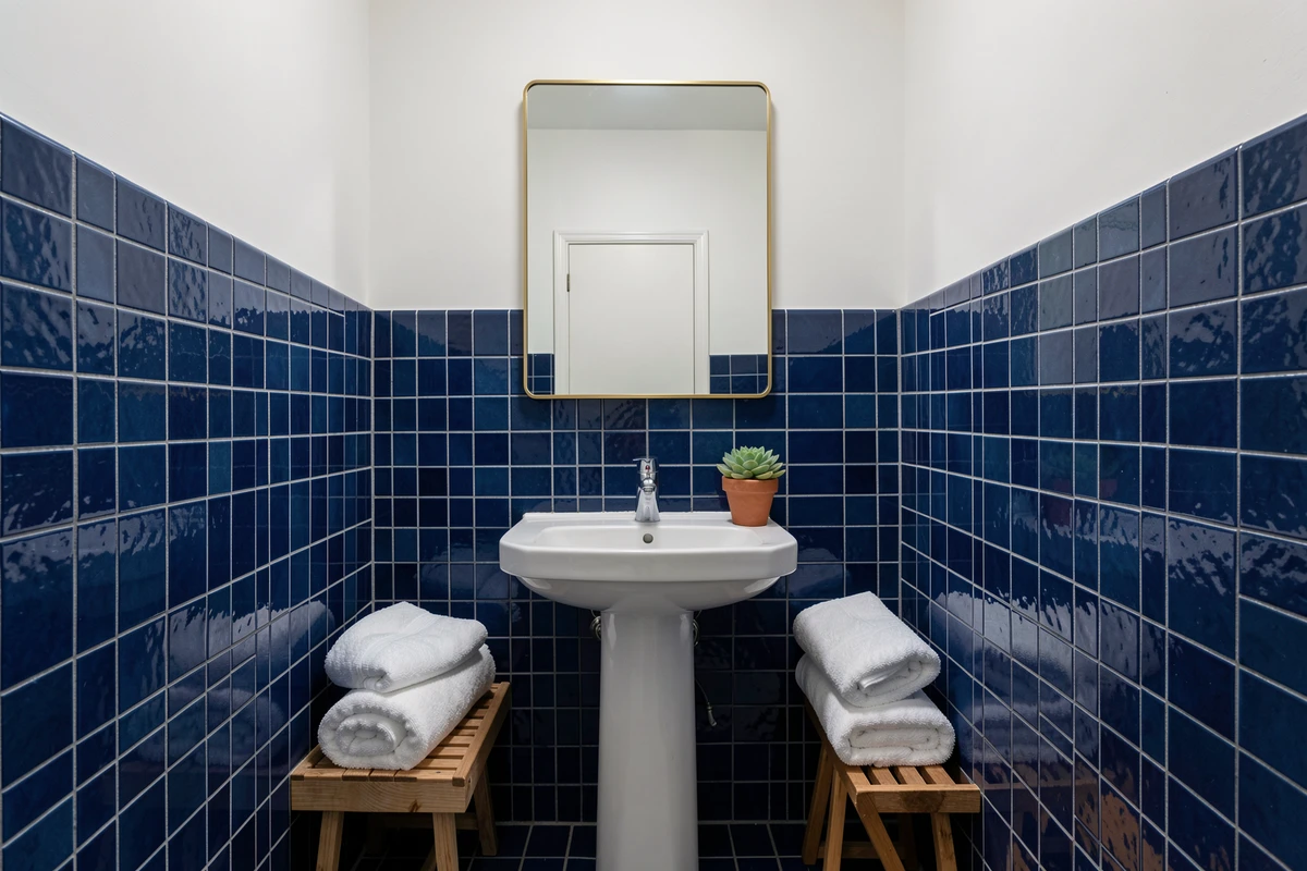 Petite salle de bain rénovée avec carrelage zellige bleu marine et accessoires en laiton et bois